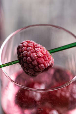 Pink sparkling cocktail with a raspberry. Glass of champagne and glitter stars on wooden table. Copy...