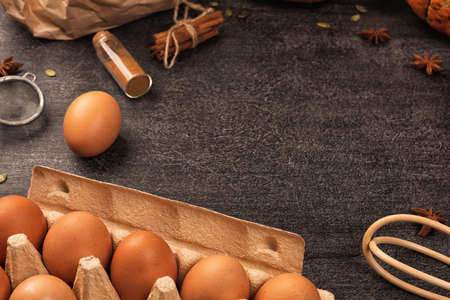 Baking ingredients for pumpkin pie or cookies. Cinnamon, flour, eggs, whisk, rolling pin on dark...
