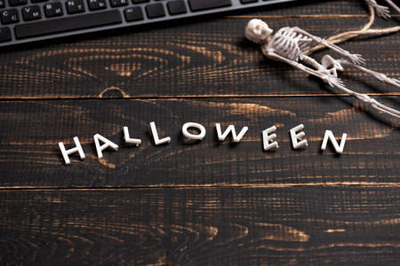 Halloween decorations with skeleton and laptop computer on dark wooden desk table. Top view, flat lay. Festival background conceptの写真素材