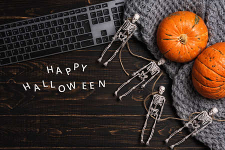Halloween decorations with skeleton and laptop computer on dark wooden desk table. Top view, flat lay. Festival background conceptの写真素材