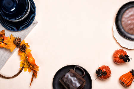 Mock up with ceramic tableware and orange pumpkin or squash on beige background. Flat lay, copy...