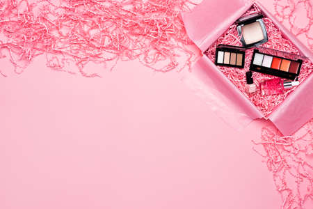Beauty box with makeup cosmetics filled with shredded pink paper packing material. Delivery of fragile object. Background and copy spaceの写真素材