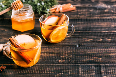 Glass cup of hot ginger tea with lemon on dark wooden table.の写真素材