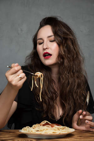 A beautiful young woman eats Italian spaghetti pastaの写真素材
