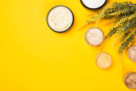 Cosmetic containers with skincare products on illuminating yellow background