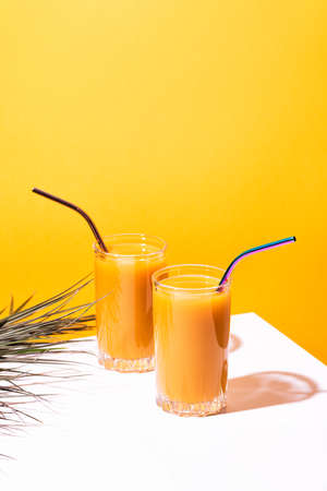 Glass of fresh mango juice cocktail and palm branchesの写真素材