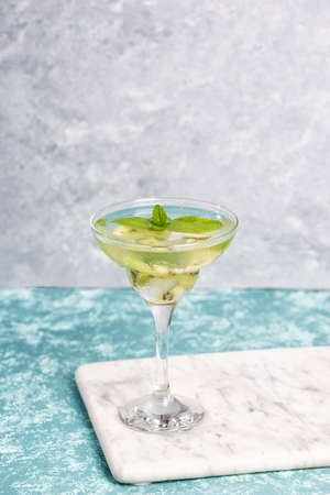 A glass of mojito cocktail with lime and mint and kiwi