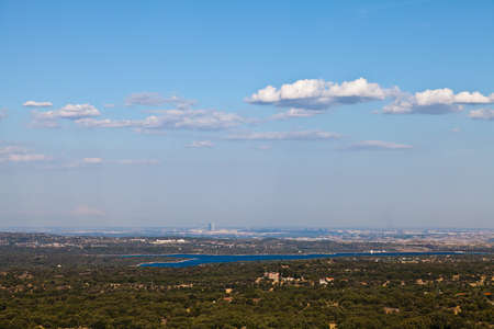 View of the city of Madrid from a distance. Bright blue lake in the foreground. Taken on a sunny day with bright blue sky and a few white clouds.の写真素材