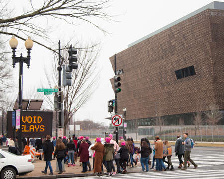 Women and men of all ages donning pink hats crossing Constitution Avenue with the new African...