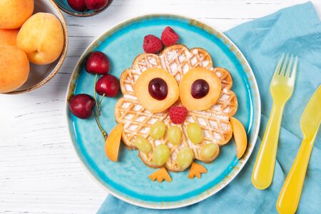 Waffle with fruits and berries in the shape of cute owl with balloons, food for kids idea, top viewの写真素材