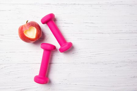 Pink dumbbells and apple with heart, fitness concept, healthy lifestyle, top viewの写真素材
