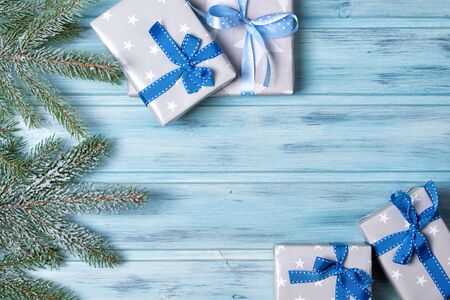 Christmas gift boxes and fir branch with snow, wooden background, top viewの写真素材