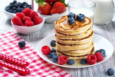 Stack of pancakes with fresh blueberry, raspberry and honey, milk and fresh berries, healthy breakfast conceptの写真素材
