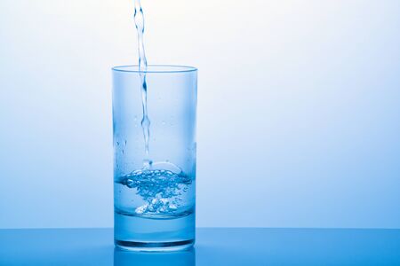 Pouring drinking water into the glass with reflectionの写真素材
