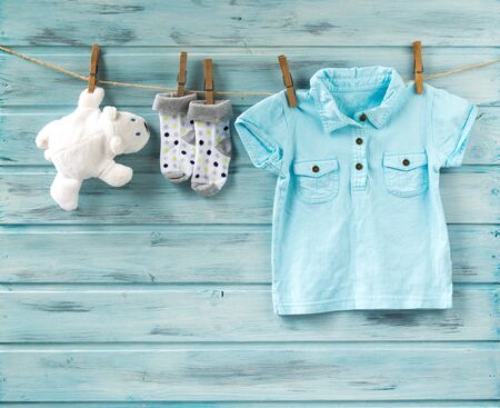 Baby boy t-shirt, socks and white toy bear on a clotheslineの写真素材