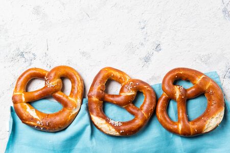 Fresh backed pretzels in a row on a blue towel, beer snack, top view with copy spaceの写真素材