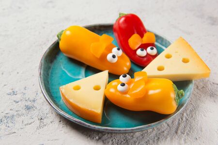 Colorful sweet mini peppers in the shape of mouses and pieces of cheese on a plate, stone table, snack for kids ideaの写真素材