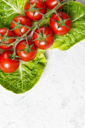 Ripe red cherry tomatoes on Romain Lettuce leaves, stone table, top view with copy spaceの写真素材