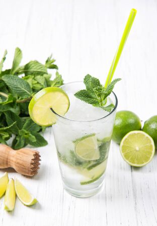 Mojito cocktail with fresh limes and mint leaves in a glass on a light gray stone backgroundの写真素材
