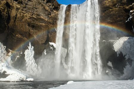 Winter landscape with famous Skogafoss waterfall with rainbow, Icelandの写真素材
