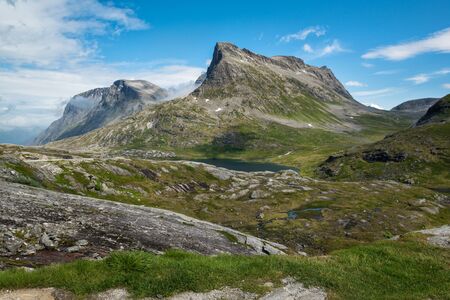 Beautiful landscape with lake and mountains covered by clouds, on the way to Trollstigen, Norwayの写真素材
