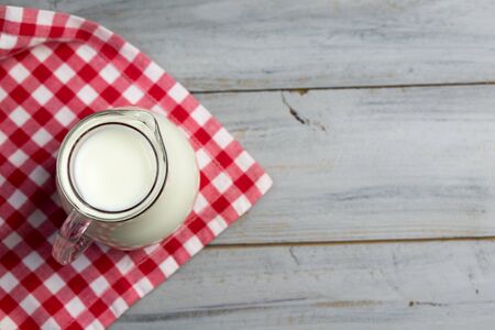 Milk in a glass jug on a wooden table, top viewの写真素材