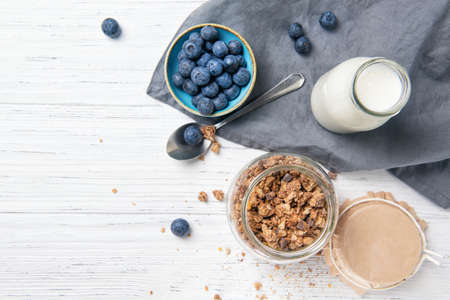 Granola muesli, milk and ripe blueberries, healthy breakfast concept, wooden background, top viewの写真素材