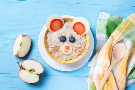 Funny oat porridge with mouse face made of fruits and berries, food for kids idea, top viewの写真素材