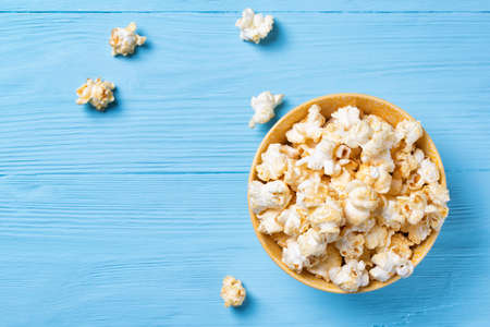 Sweet popcorn in a yellow bowl on a blue wooden background, top viewの写真素材