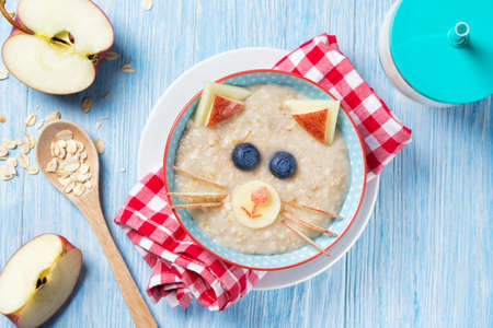 Funny oat porridge with cat, kitten face made of fruit and berries, food for kids idea, top viewの写真素材