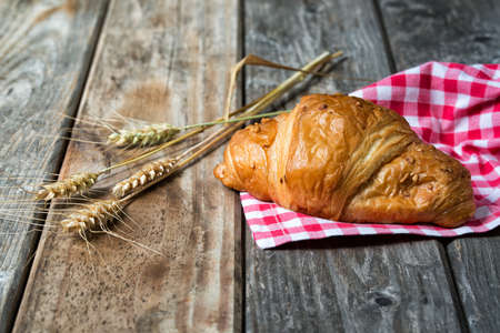Croissant with nuts on textile and spikelets, wooden backgroundの写真素材