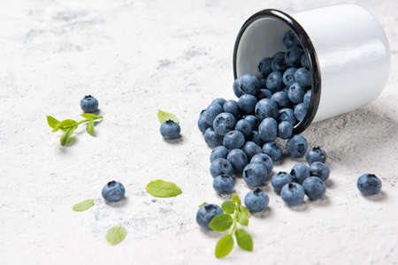 Fresh ripe blueberries in enameled cup, stone table backgroundの写真素材
