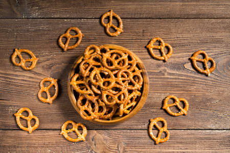 Wooden bowl full of mini pretzels with salt on wooden background, top viewの写真素材