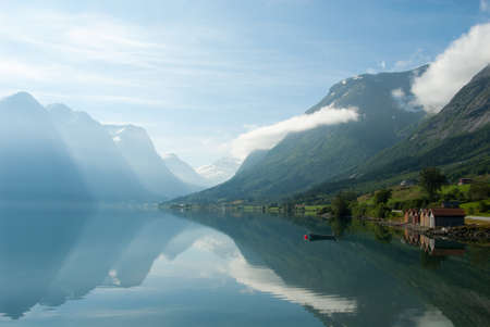 Landscape with mountains reflecting in the lake and small boat near the shore, Norwayの写真素材
