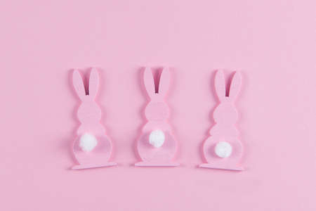 Pink Easter bunnies with white tails on pink background, easter greeting card, top view