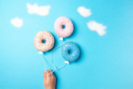 Colorful donuts on blue background, creative food minimalism, donuts in a shape of ball in the sky with clouds made of sugar, top viewの写真素材