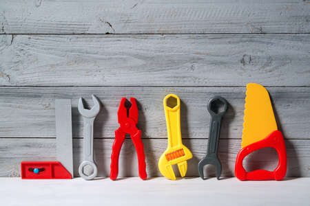 Set of plastic toy tools for children in a line on a wooden background