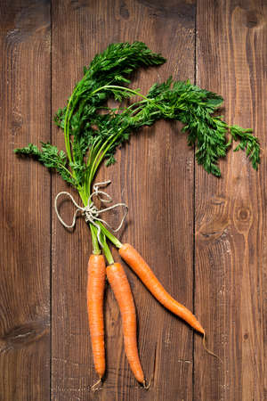 Fresh carrots bunch on rustic wooden tableの写真素材