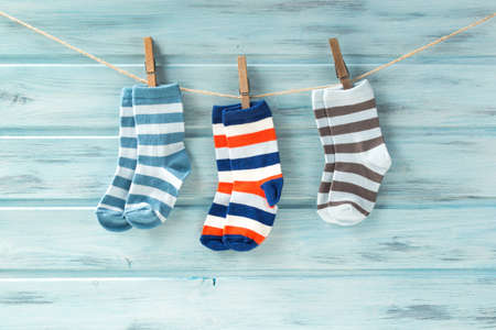 Baby striped socks on a clothesline on wooden backgroundの写真素材
