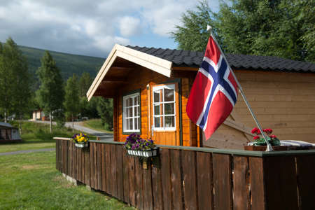 Wooden cottage with Norwegian flag, camping house, Norway