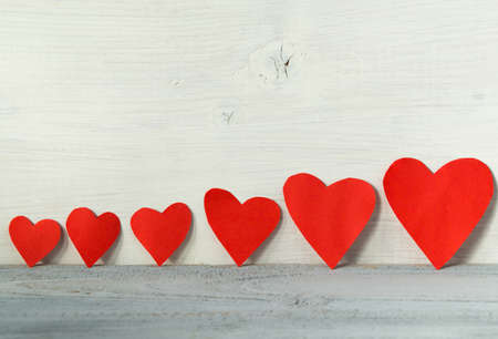 Valentines day background, red hearts in a line on a light wooden background