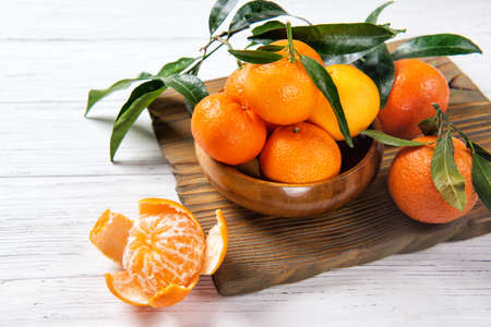 Mandarine or tangerine with leafs on wooden table, winter fruitsの写真素材