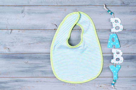 Baby bib and word baby on wooden background