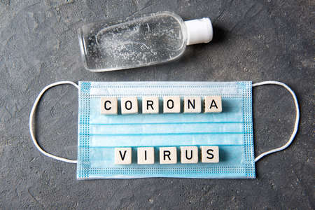 Blue face mask with letters corona virus and bottle with hands disinfectant, top view, health conceptの写真素材