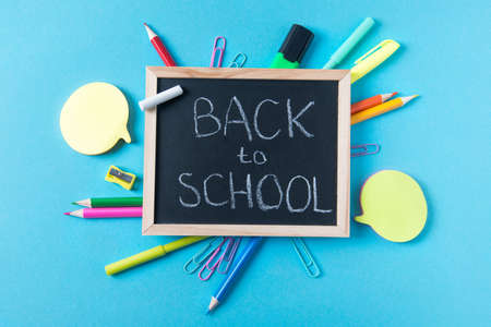 School chalkboard with back to school text and various stationery accessories, Back to school concept, top view, blue backgroundの写真素材