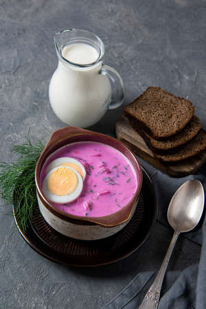 Cold beetroot soup okroshka with kefir served with boiled eggs, dill and bread slices, rustic backgroundの写真素材