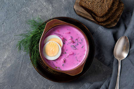 Cold beetroot soup okroshka with kefir served with boiled eggs, dill and bread slices, rustic...