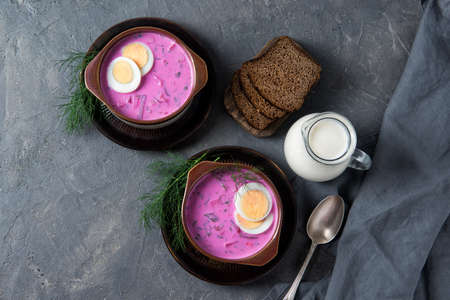 Cold beetroot soup okroshka with kefir served with boiled eggs, dill and bread slices, rustic background, top viewの写真素材