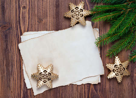 Christmas greeting card with old blank paper sheet, fir and snowflakes, wooden backgroundの写真素材