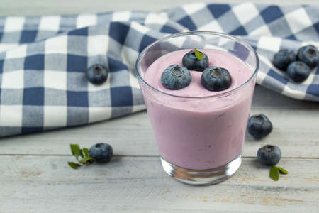 Glass with blueberry yogurt and fresh berries on wooden tableの写真素材